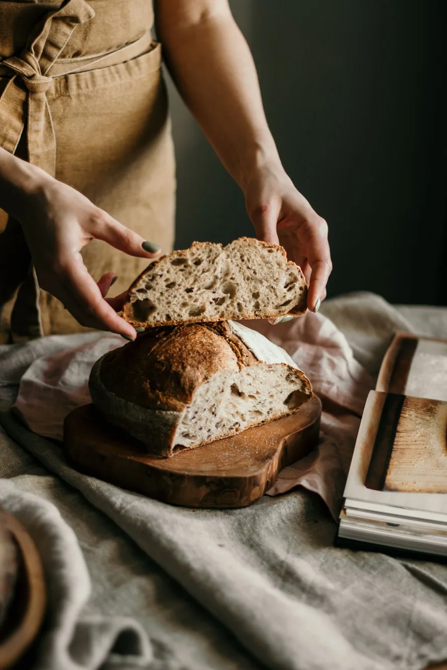 A baker tearing open a fresh loaf of sourdough